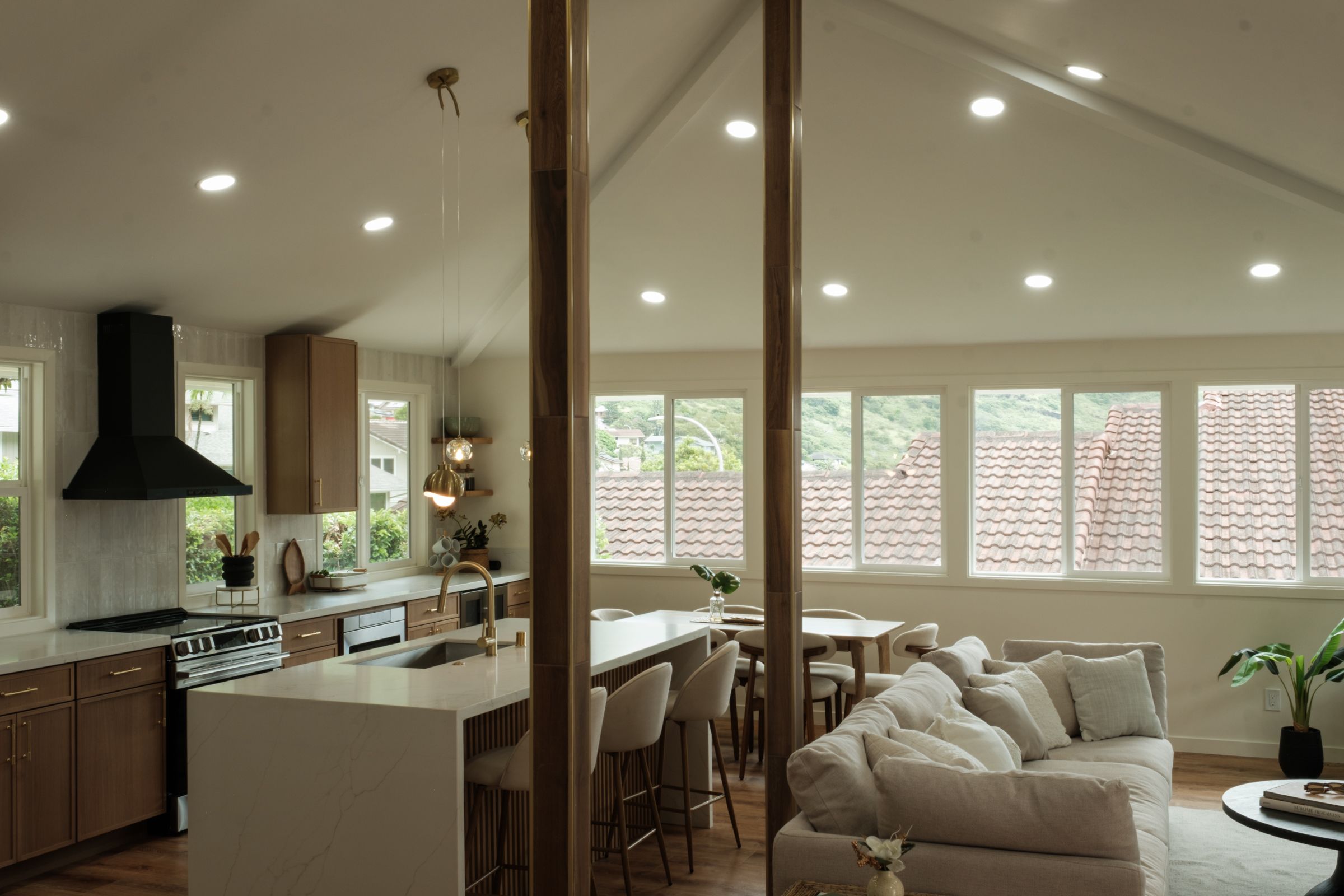 View into an open kitchen and living area with pendant lighting, wood cabinetry, and neutral seating.