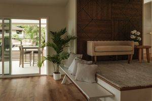 Living room with wood flooring, neutral seating, and an open doorway leading to an outdoor dining area.