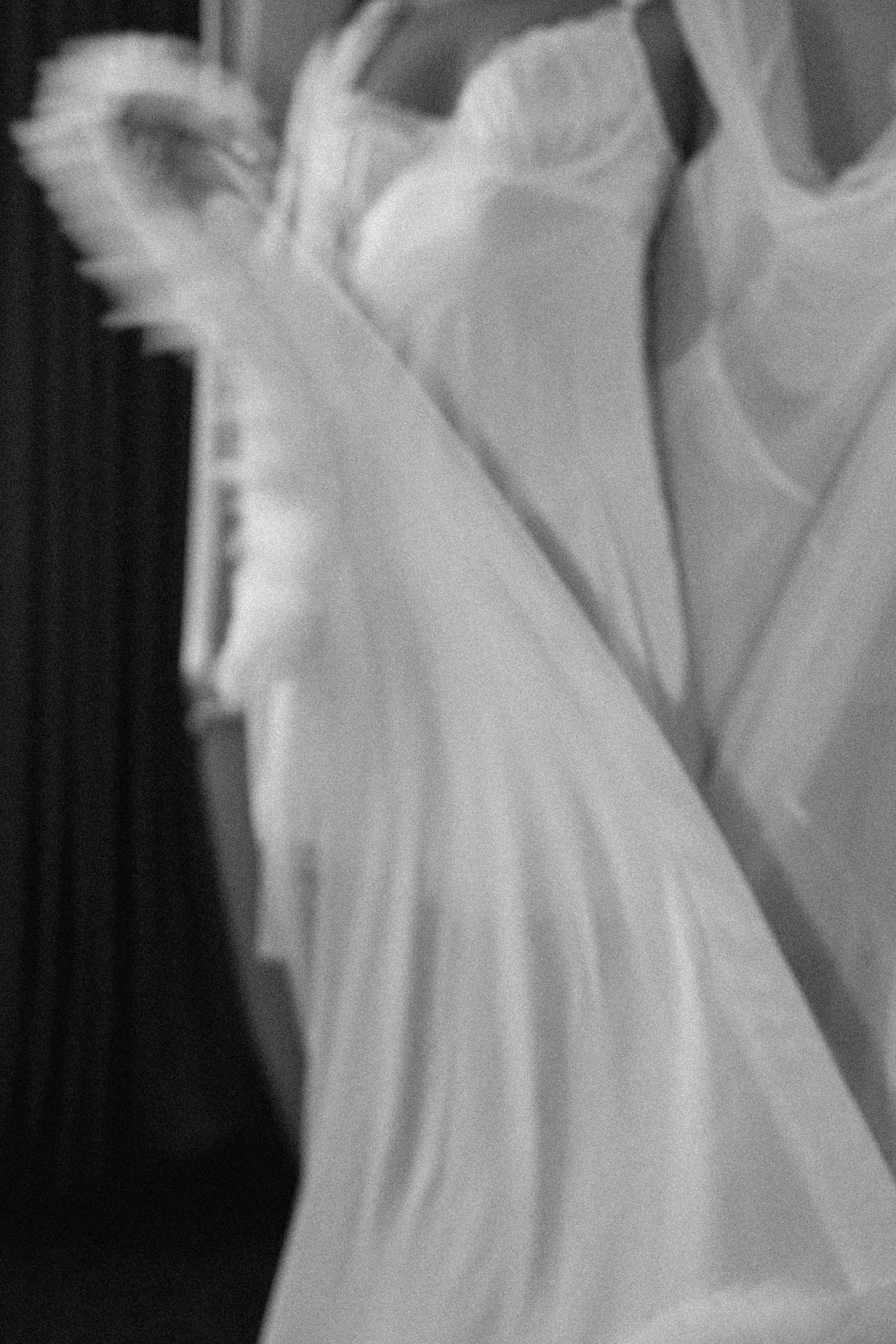 Black and white photo of flowing white fabric draped elegantly, capturing motion and texture in soft focus.