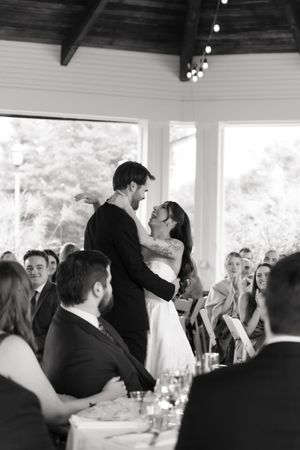 Black and white photo of a bride and groom sharing their first dance at a wedding reception.