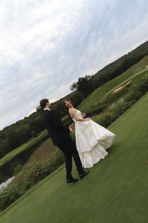 Bride and groom share a romantic dance on lush green golf course with scenic landscape backdrop.