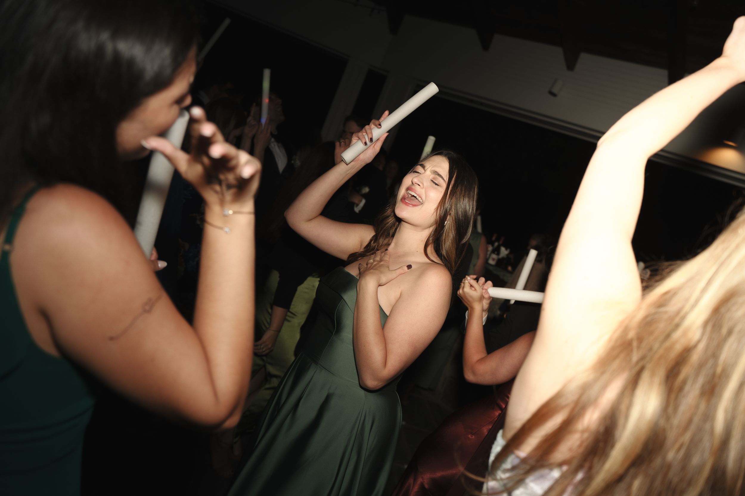 Women dancing and celebrating at a lively nightclub party in green dresses.