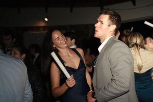 A woman in a navy dress and a man in a gray suit share a conversation at an elegant evening party.