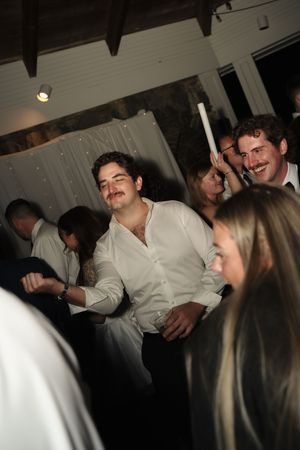 Guests dancing and celebrating at a lively indoor wedding reception with white drape decorations.