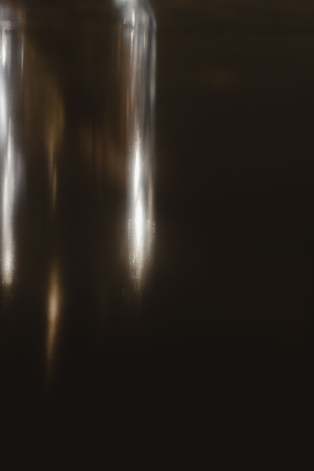Blurred abstract dark background with streaks of white and golden light creating an atmospheric bokeh effect.