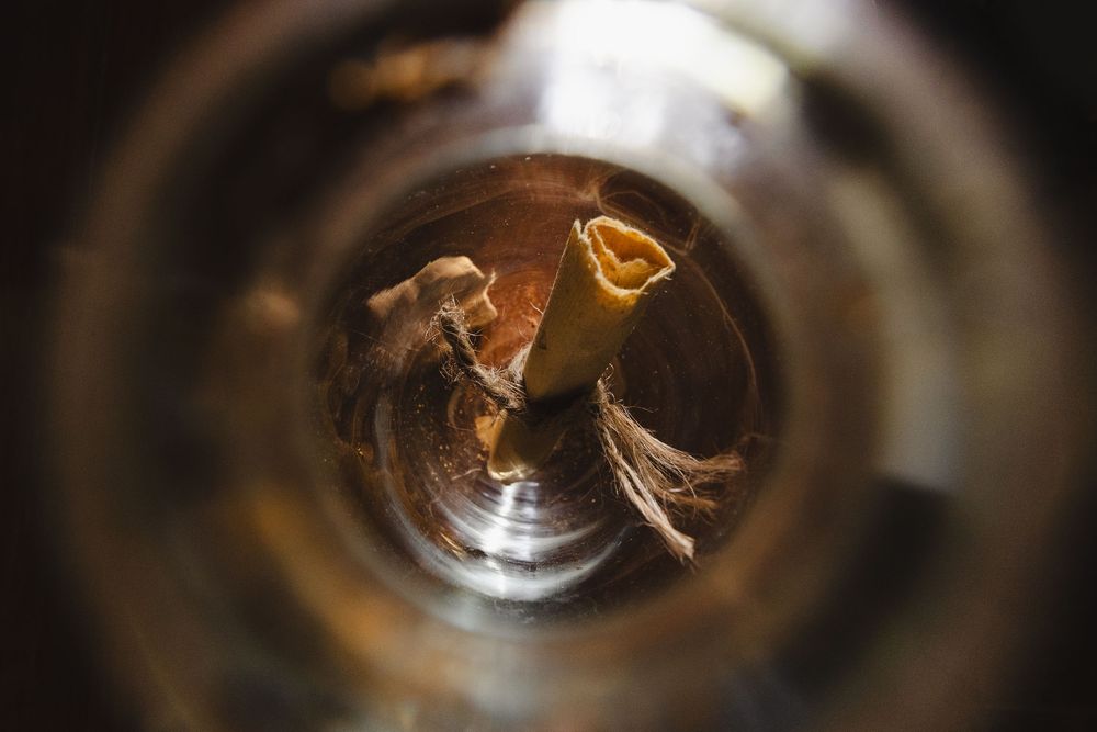 Close-up view looking down into a glass bottle containing a rolled paper tube.