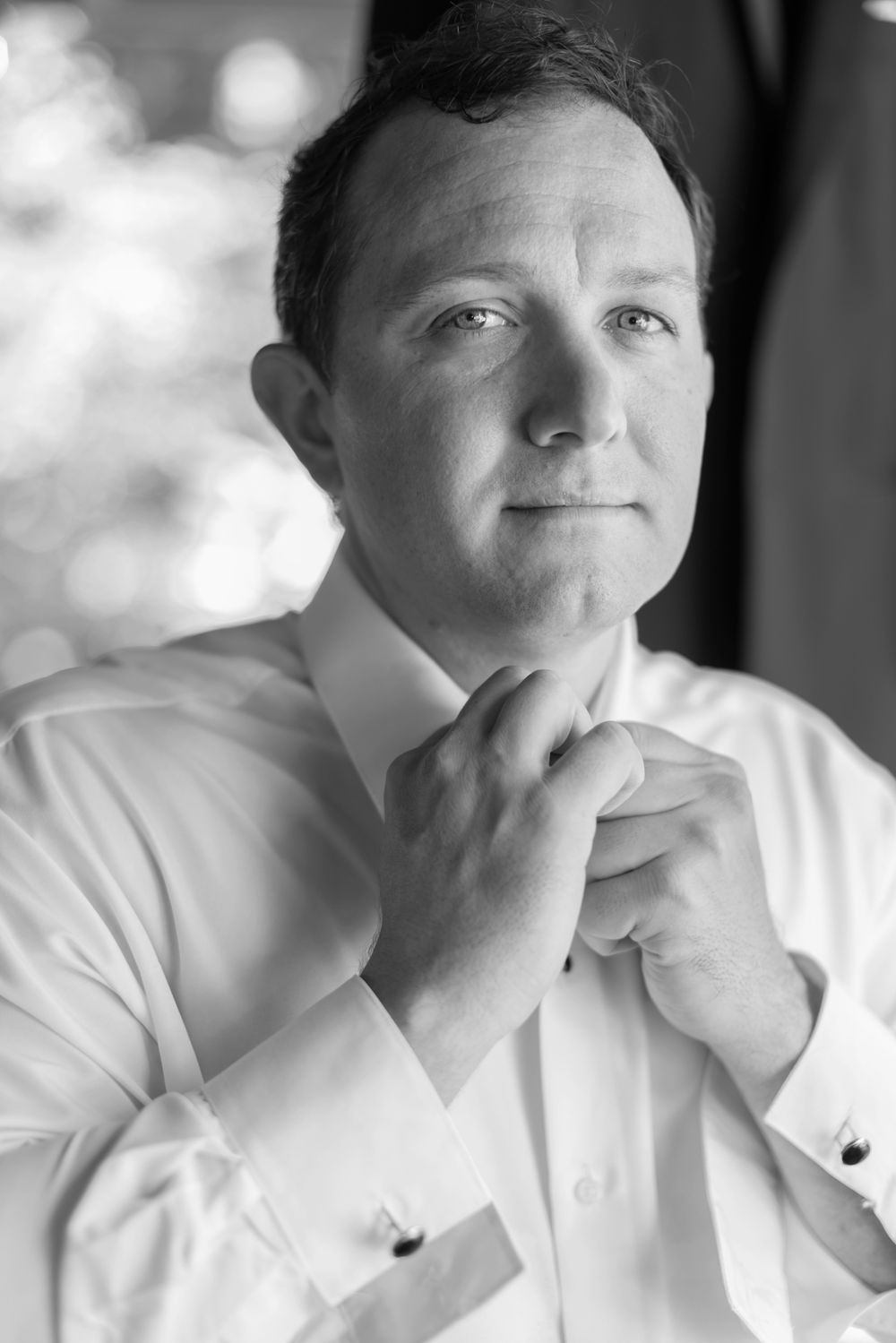 Black and white portrait of groom getting ready as he puts on bow tie for wedding. Seacoast Hampton Concord wedding photographer