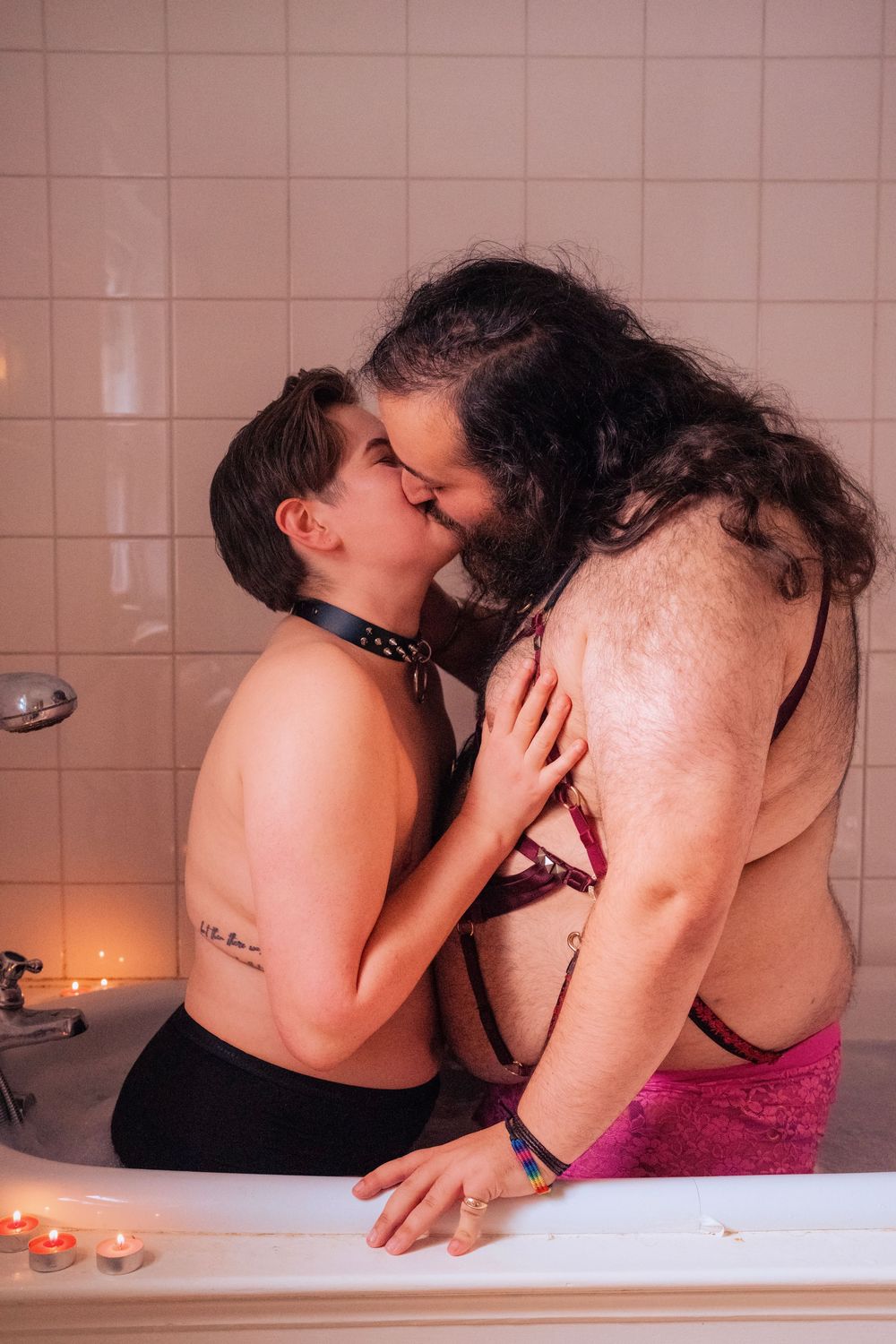 Two people sharing an intimate kiss in a candlelit bathtub, creating a romantic and cozy bathroom atmosphere.