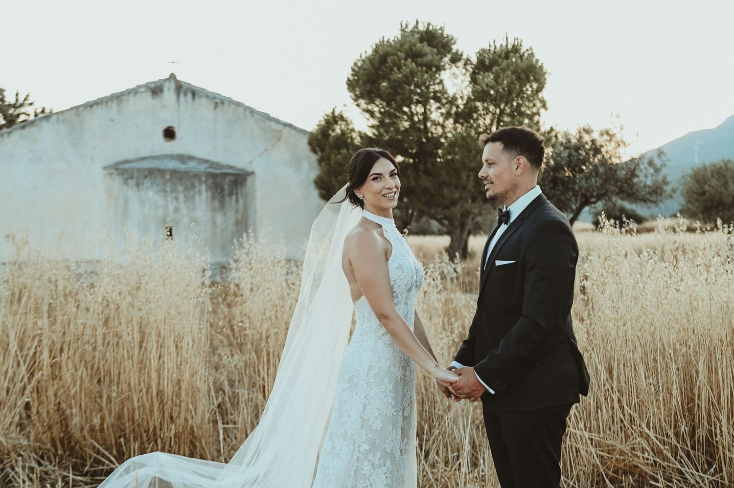 Black and white wedding photo of bride and groom gazing at each other outdoors among trees.