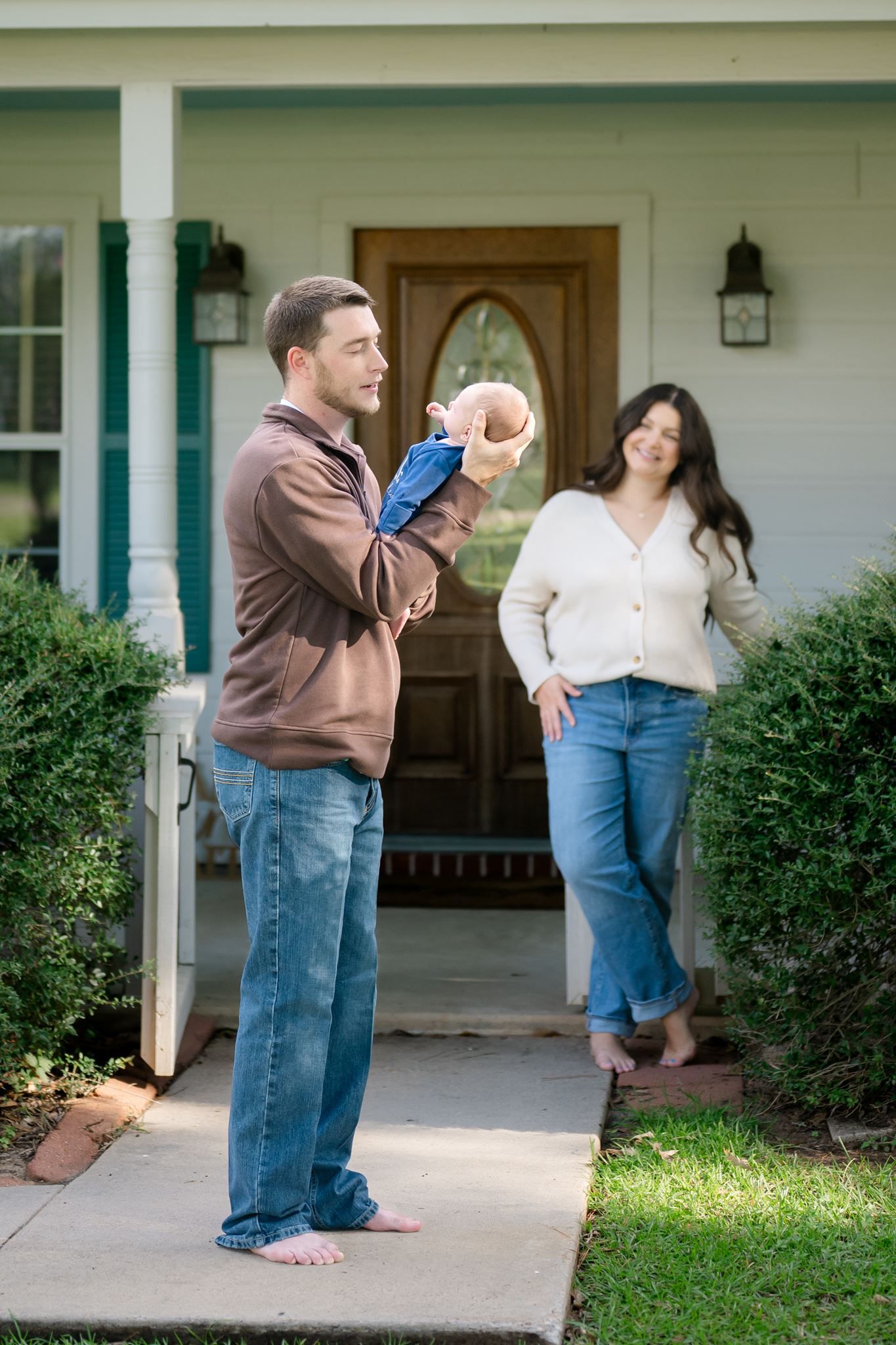 New parents holding their three-week-old baby boy on the porch of their Willis Texas home