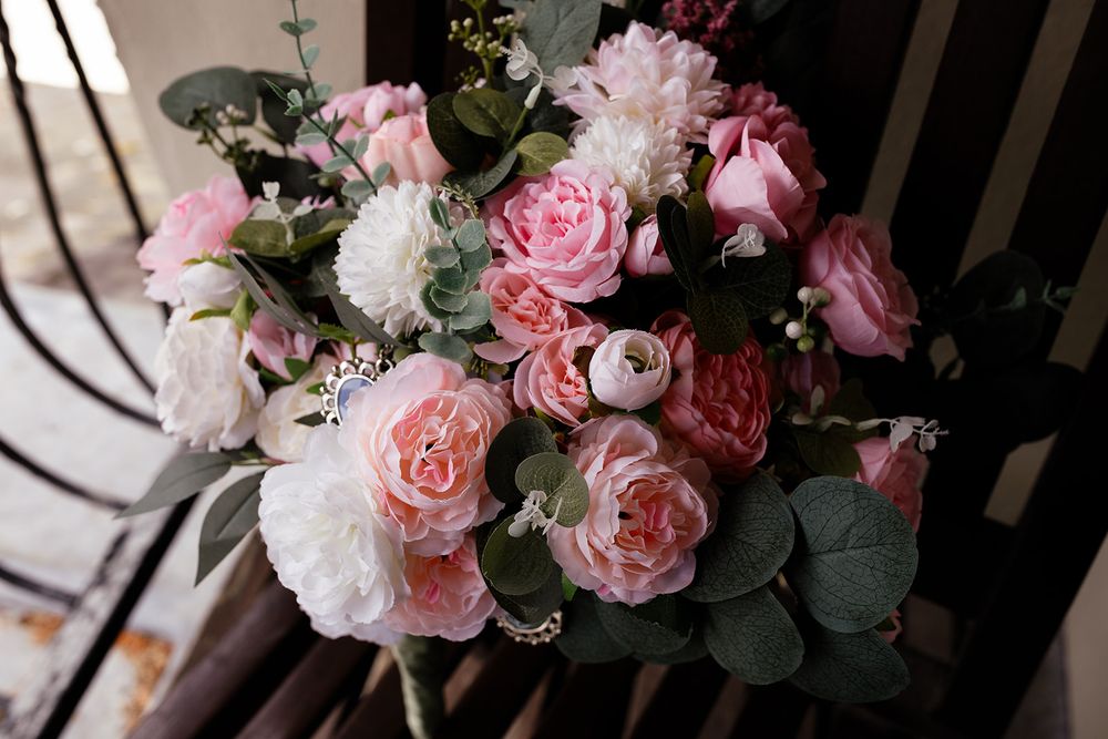 A beautiful bridal bouquet featuring pink roses, white peonies, and eucalyptus greenery arranged elegantly.