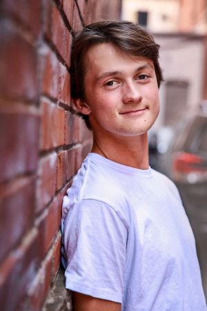 Casual portrait against red brick wall in urban setting.