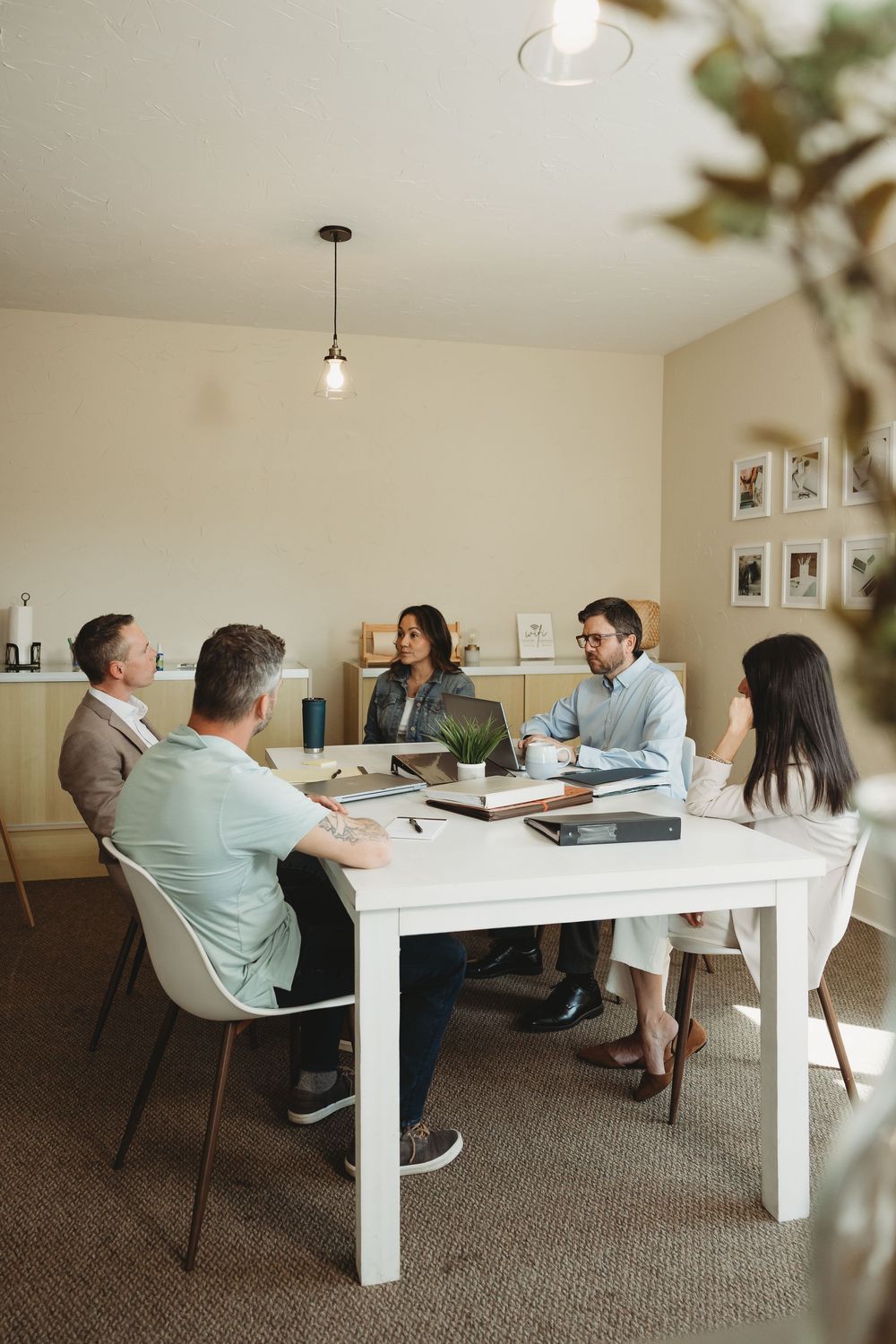 Diverse group of five business professionals having a meeting around a white table in a bright modern office.