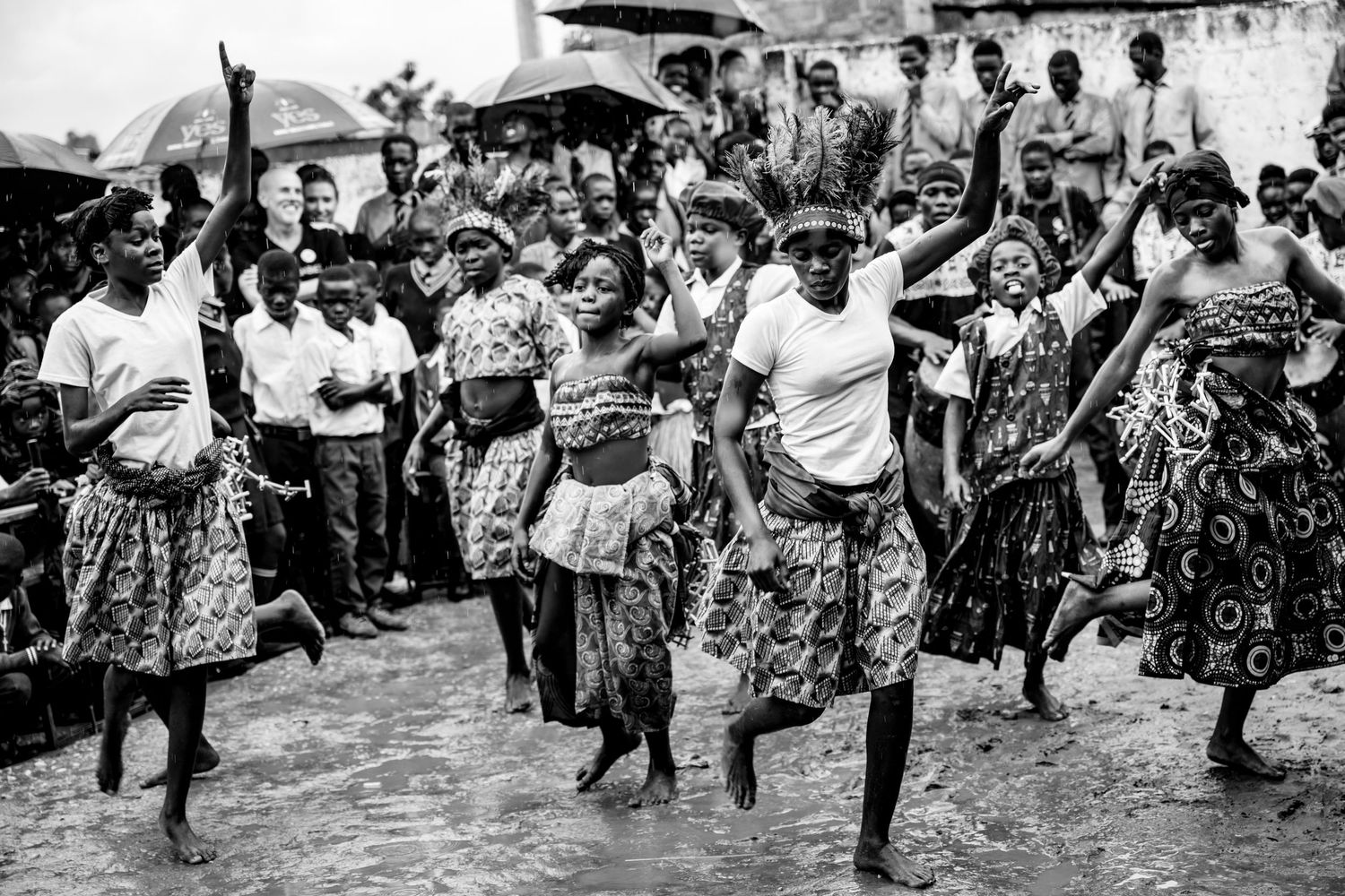 Blurred motion shot of women in vibrant colorful African print dresses dancing energetically at a traditional cultural celebration.