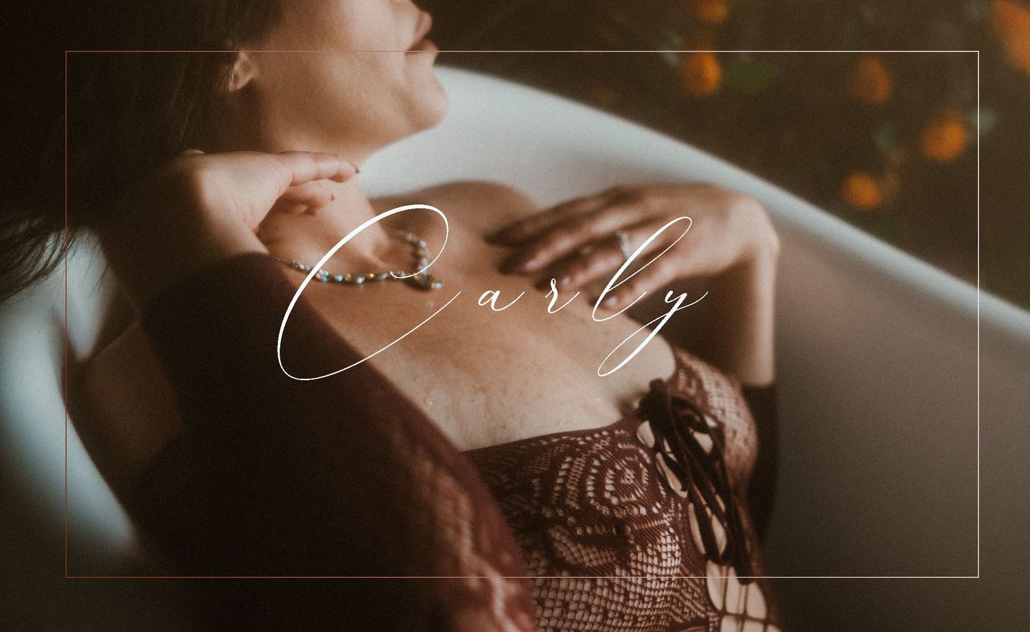 An up-close portrait of a woman sitting in a tub, softly running her hands over her chest and neck