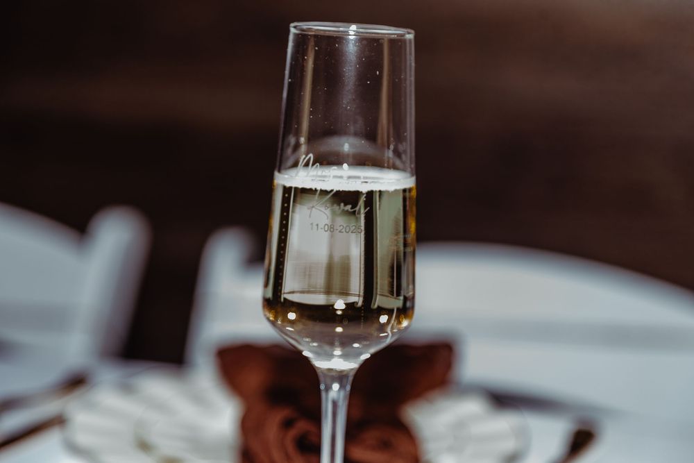 A elegant champagne flute filled with sparkling wine at a formal dinner table setting.