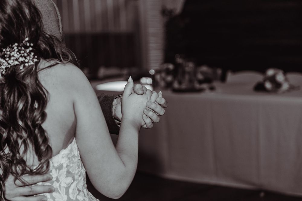 Black and white photo of a bride sharing a slow dance during her wedding reception.