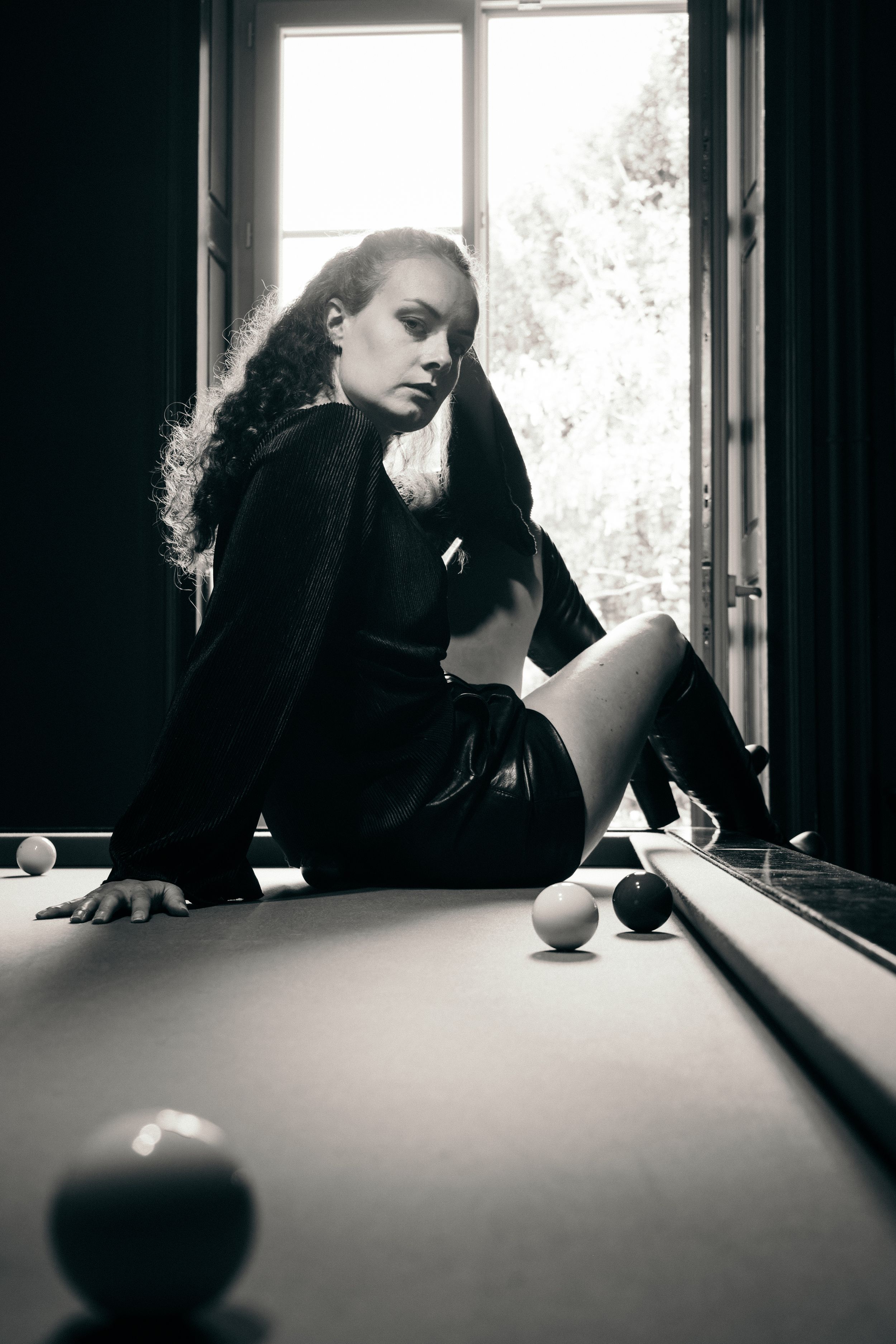 Portrait en noir et blanc réalisé autour d'une table de billard à la lumière naturelle.
