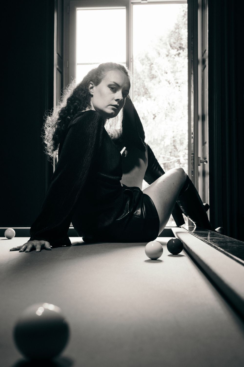 Portrait en noir et blanc réalisé autour d'une table de billard à la lumière naturelle.
