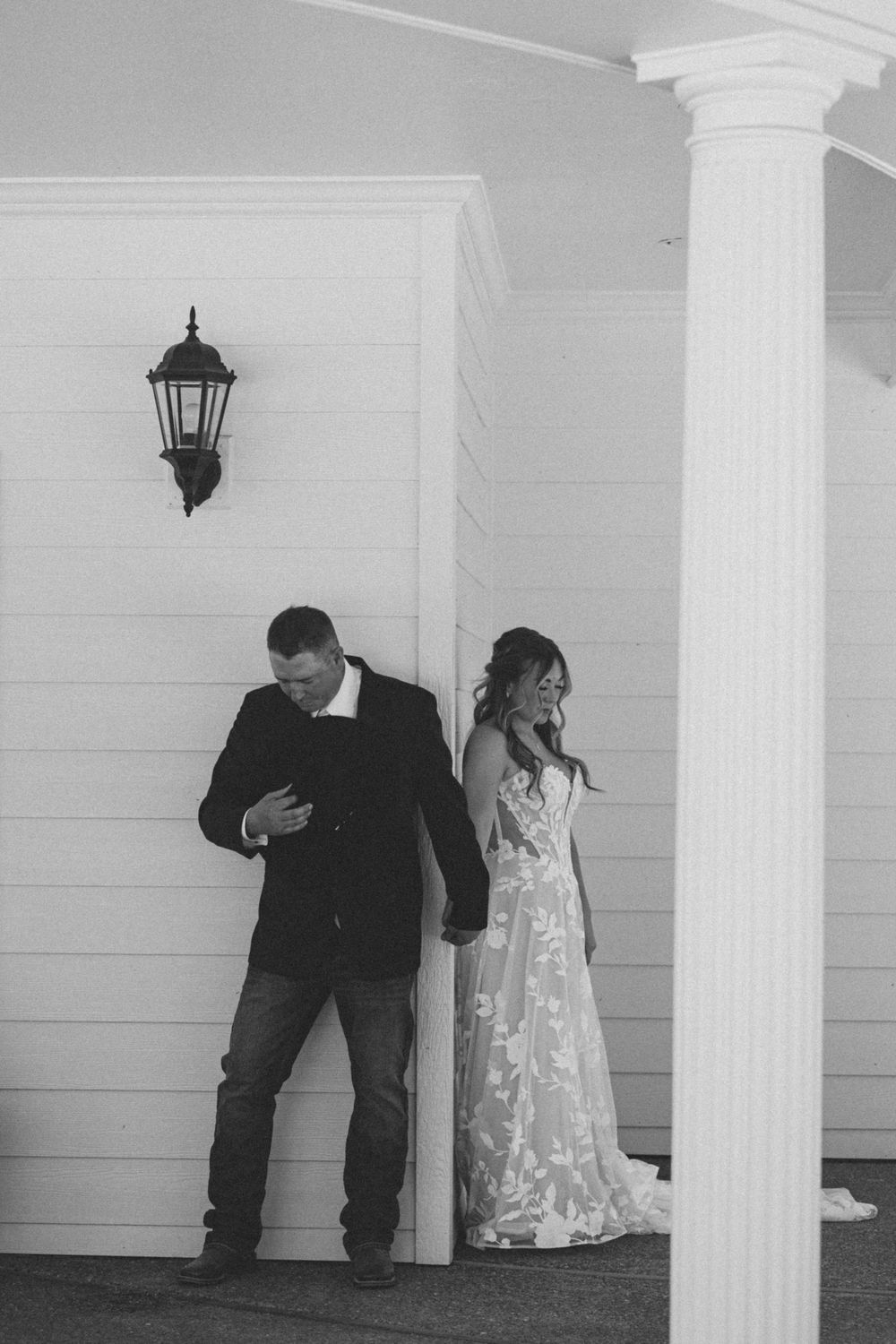 Black and white photo of bride and groom sharing a private first look moment on a porch before their wedding ceremony.