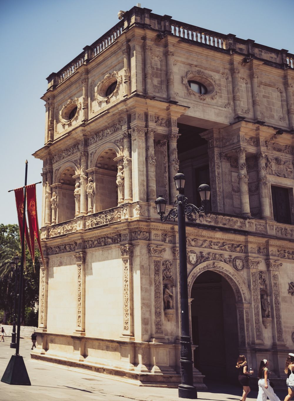 Elaborate Renaissance facade of a historic Spanish building with ornate carvings, arched entrance, and decorative balconies under clear sky.