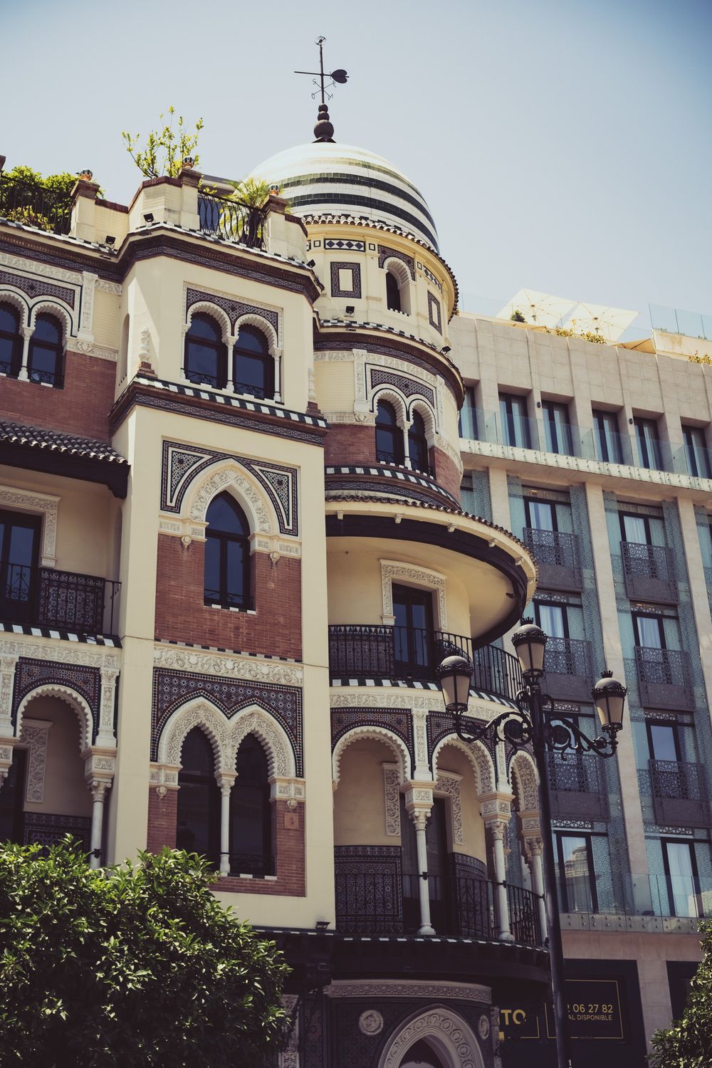Moorish-influenced Spanish building with horseshoe arches, ornate details, rounded tower with dome, and decorative brickwork patterns.