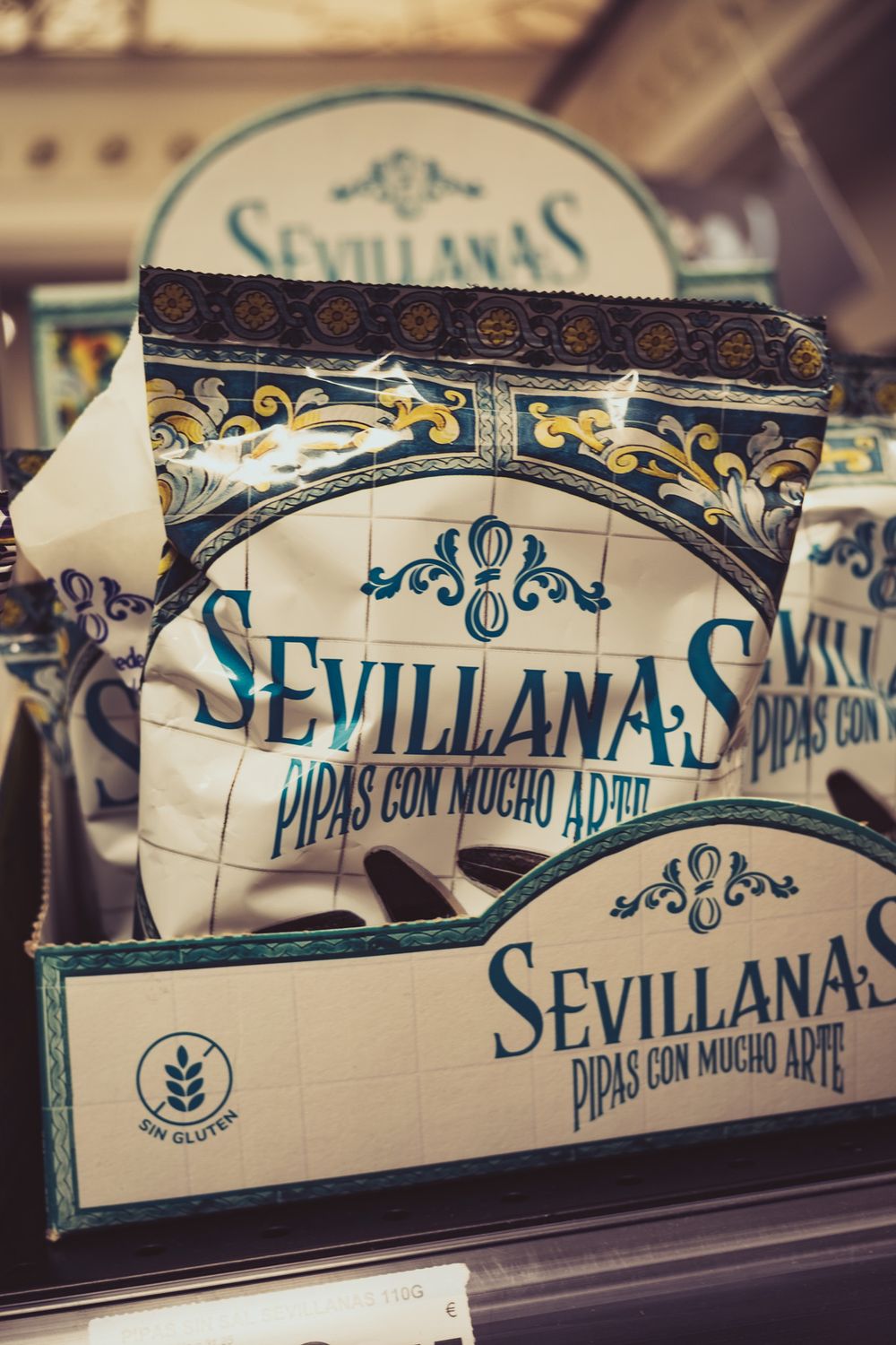 Packages of Sevillanas pipas sunflower seeds with decorative Spanish tile-inspired packaging displayed in a retail shop.