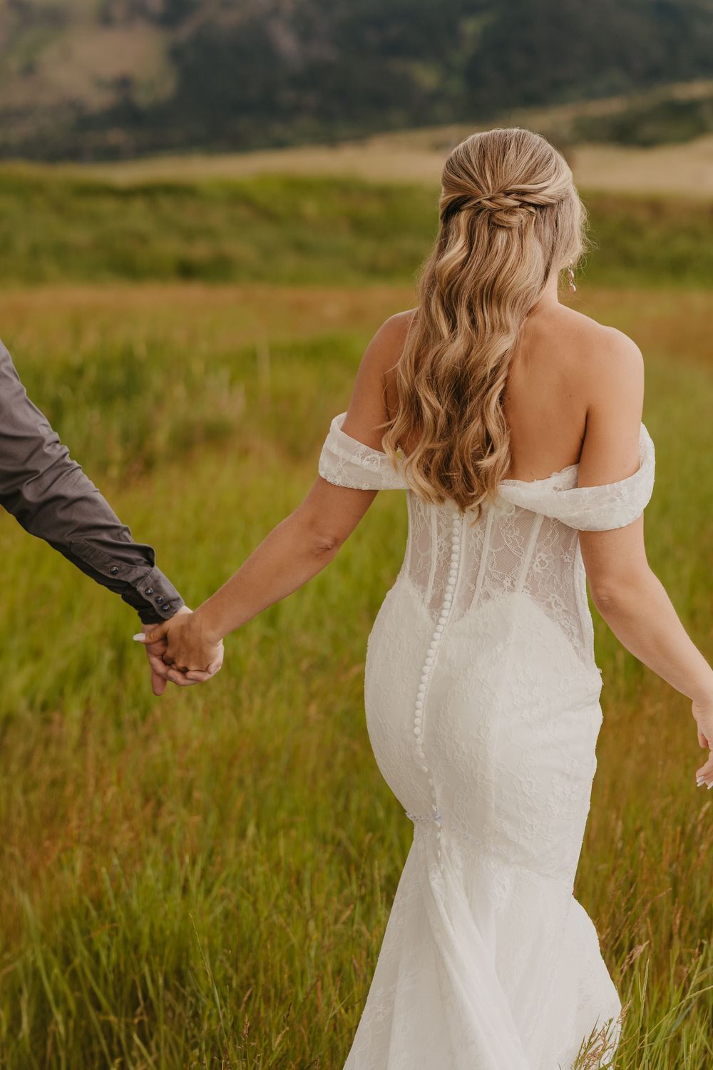 Bride and groom walk hand in hand under the mountains at Copper Rose Ranch by local Copper Rose Ranch Wedding Photographer