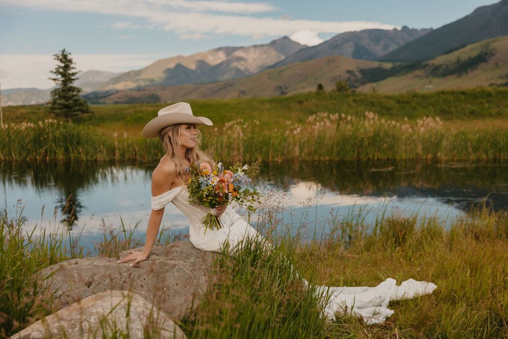 Bride poses on rock with her Stetson Cowboy Hat with the mountains at Copper Rose Ranch in Pray, Montana Captured by Livingston Photographer