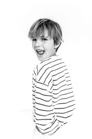 Black and white portrait of a laughing boy with blonde hair wearing a striped long-sleeve shirt.