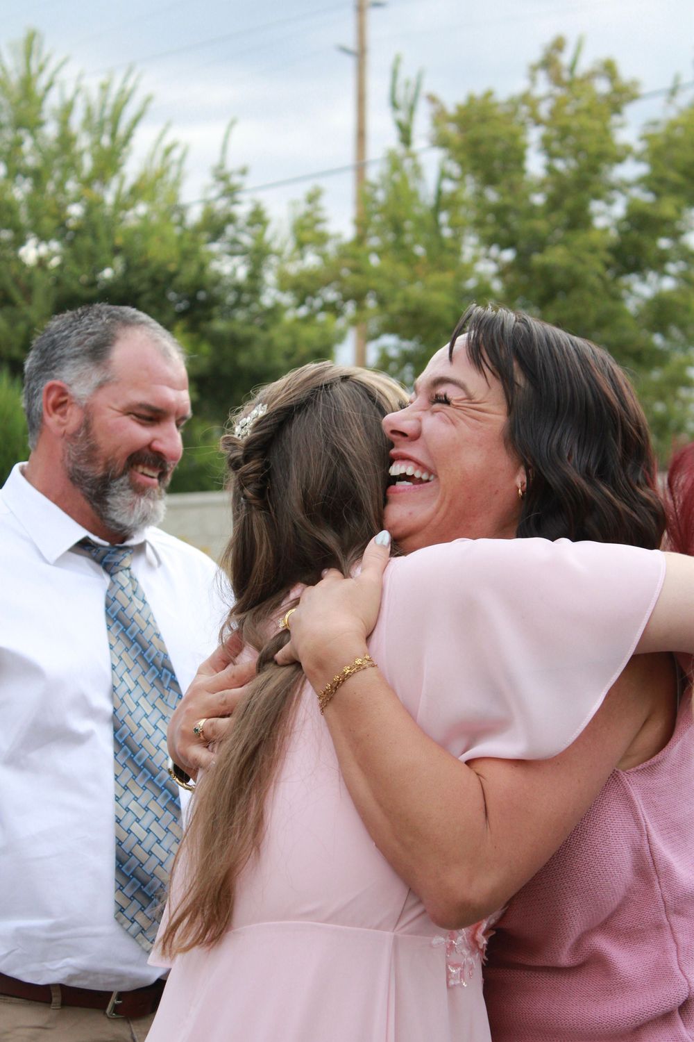 Candid moments of laughter and hugs shared during an outdoor celebration.