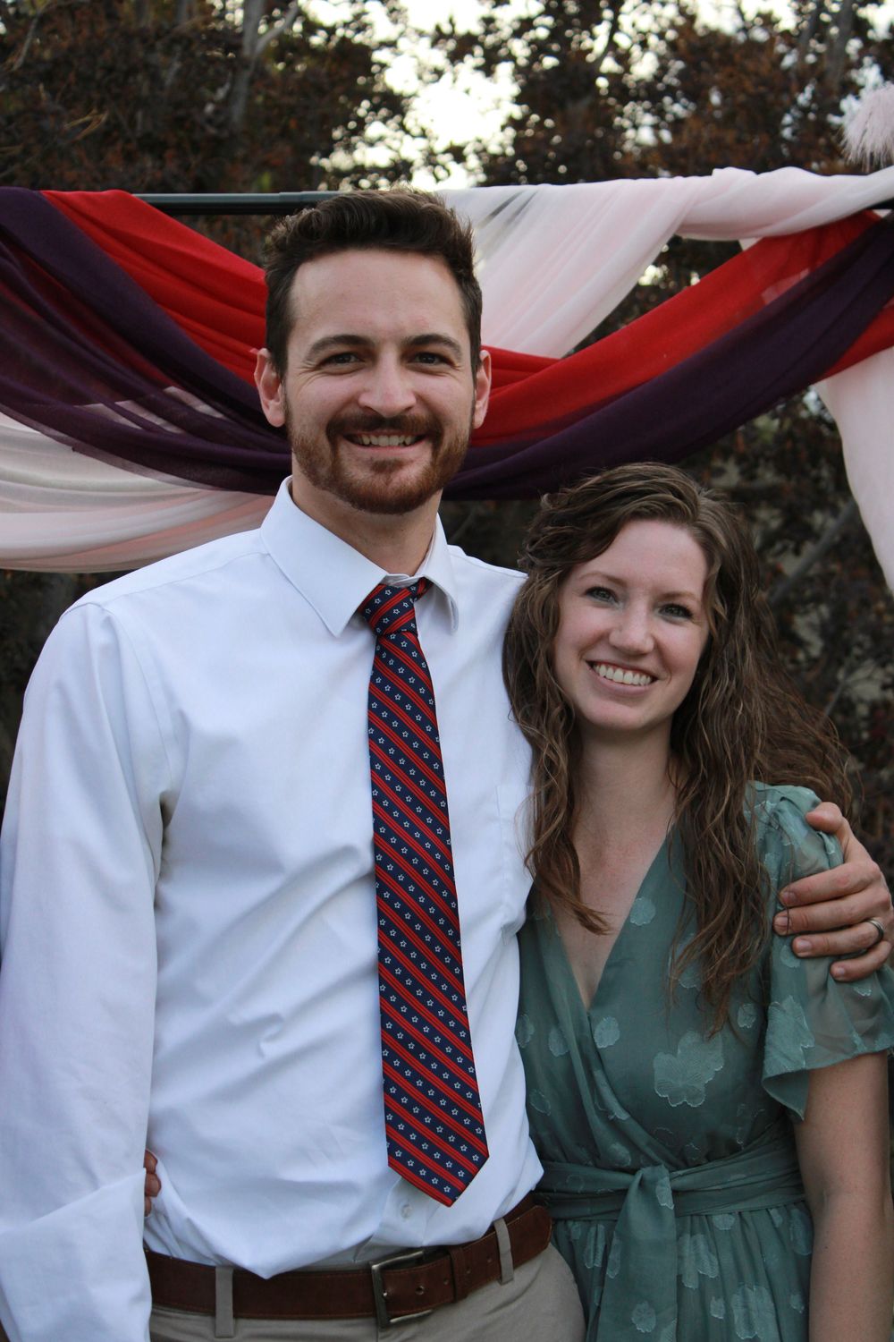 People in formal attire sharing joyful moments under decorative red and white draping.