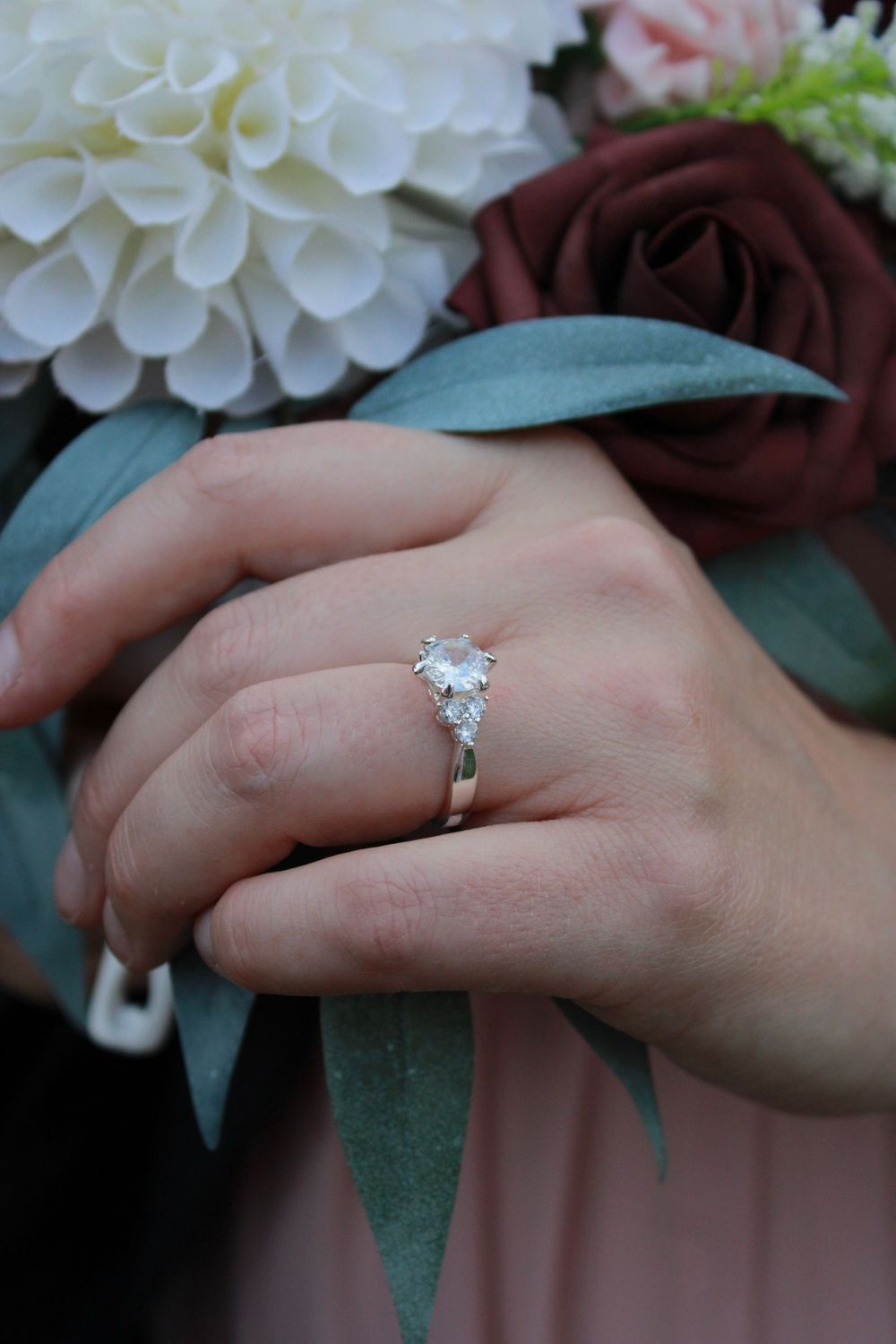 Close-up sequence showing an engagement ring with a sparkling diamond on a hand with floral background.