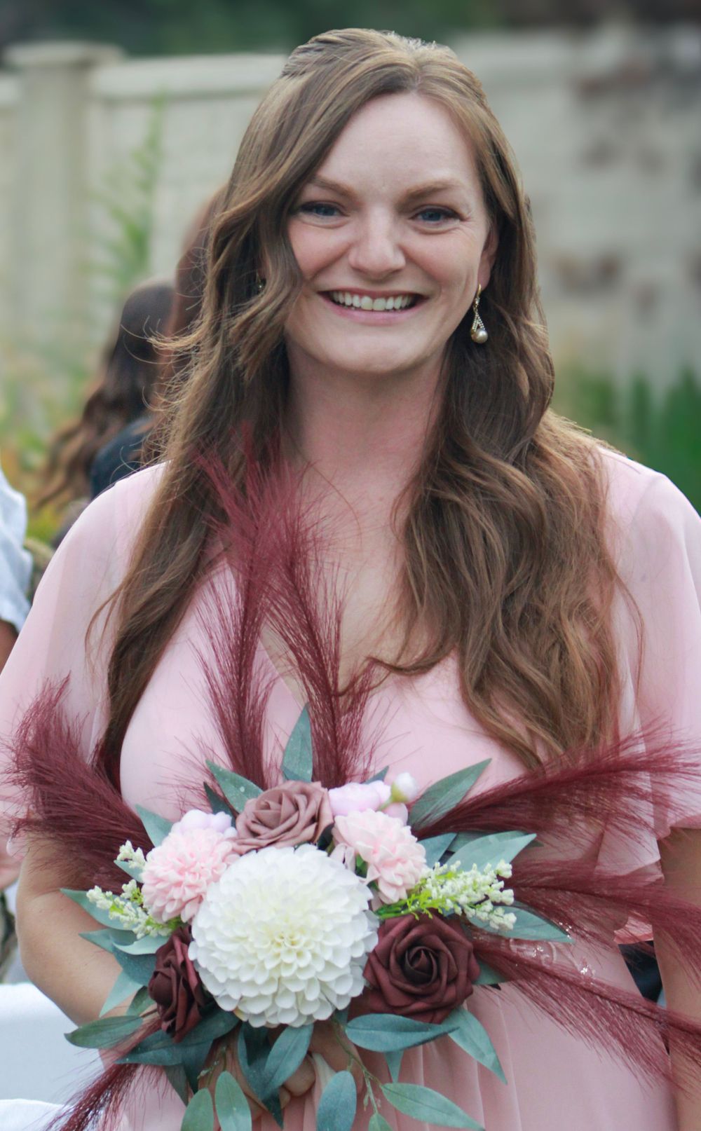 A series of photos showing a bridesmaid in a pink dress holding a white and burgundy floral bouquet at a wedding.