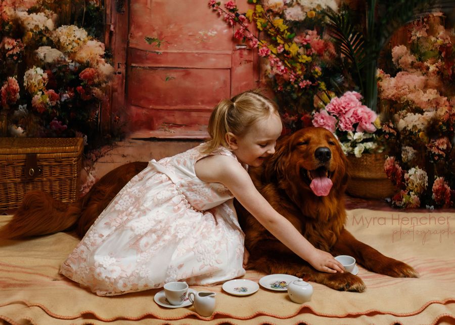 Whimsical portrait setup with floral decorations against red door backdrop.