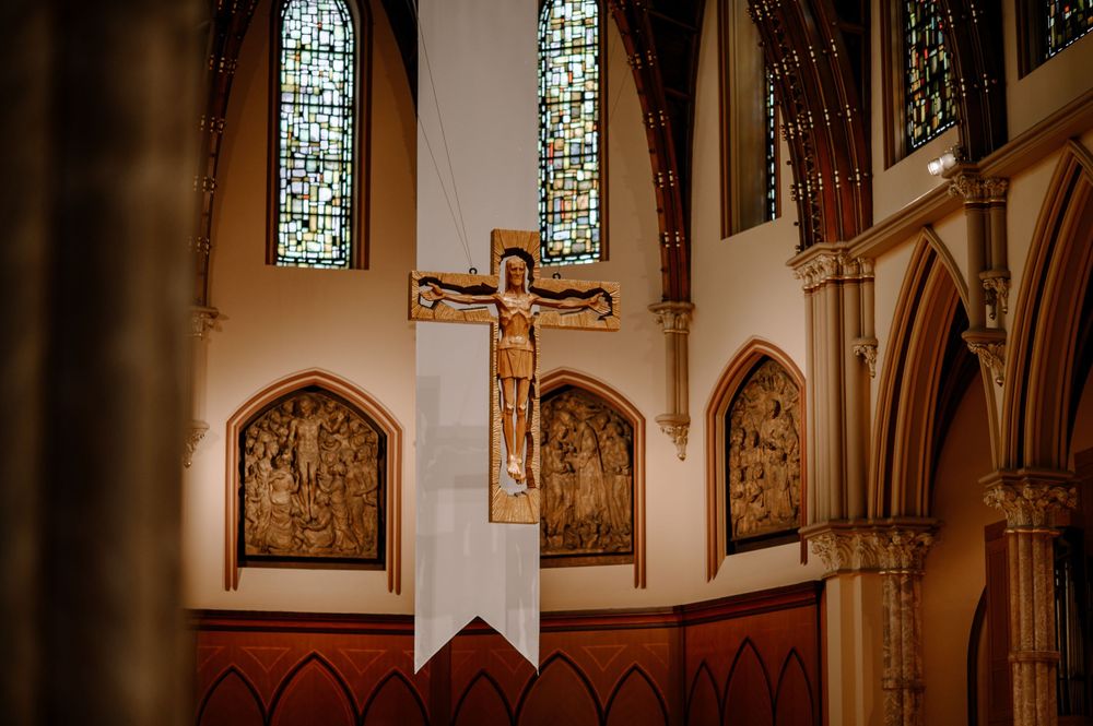 Ornate church altar featuring golden crucifix, stained glass windows, and decorative religious panels.