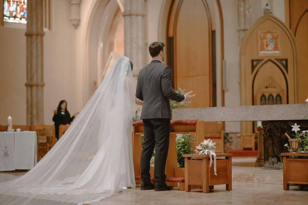 Bride in long veil and groom standing at church altar during wedding ceremony.