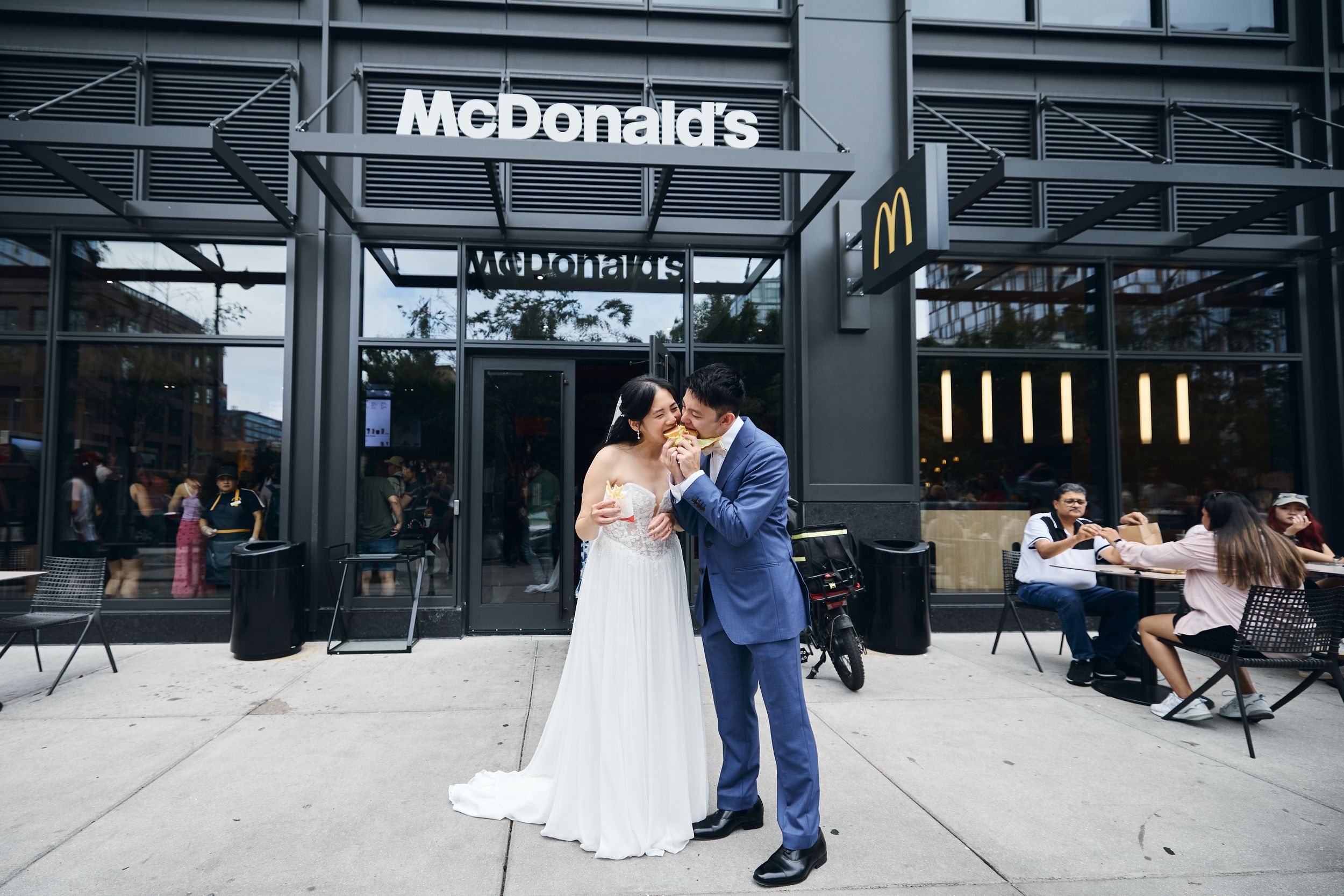 Bride and groom sharing a romantic kiss outside a McDonald's restaurant on their wedding day.