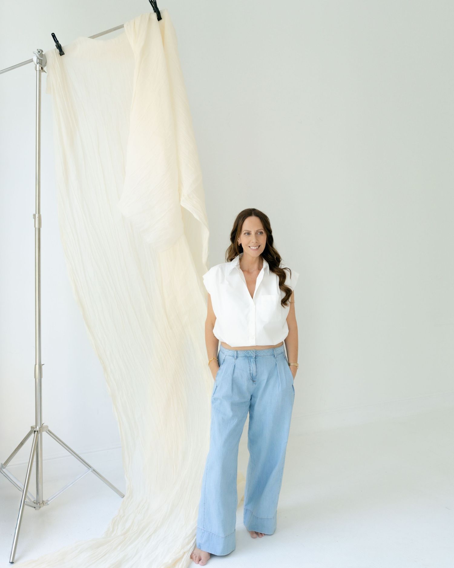 Person sitting on white couch in minimalist white room setting.