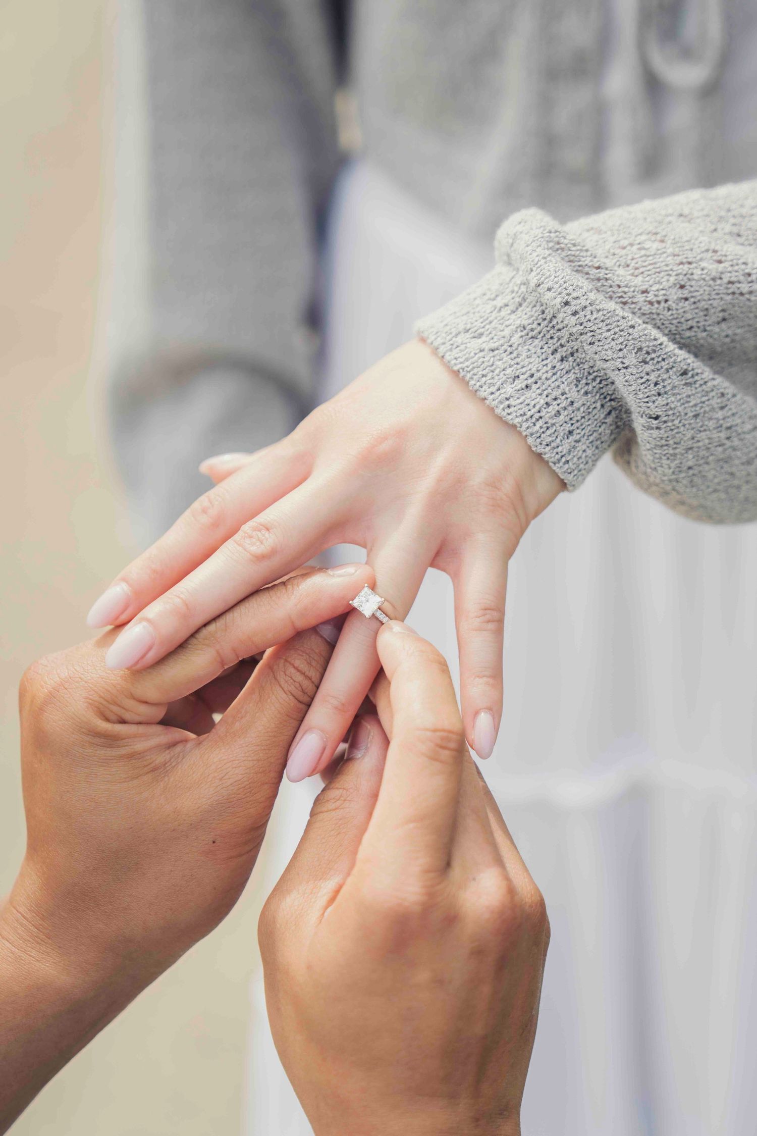 Person sliding a diamond engagement ring onto a partner's finger during a romantic proposal moment.
