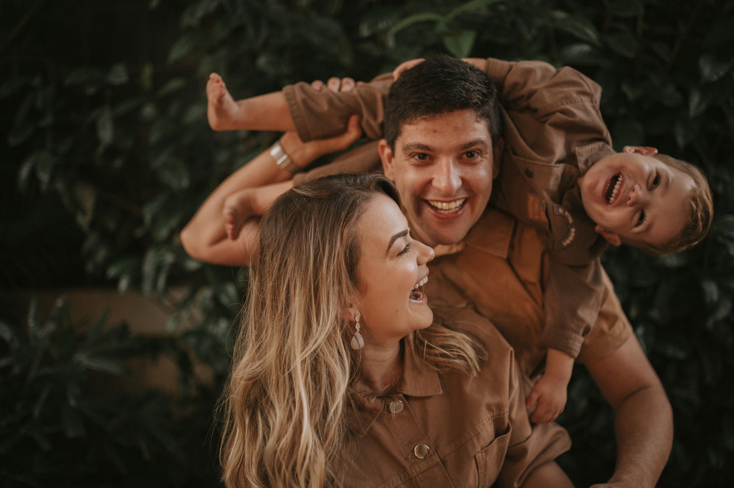 Joyful outdoor family moment with earthy brown tones and natural backdrop.