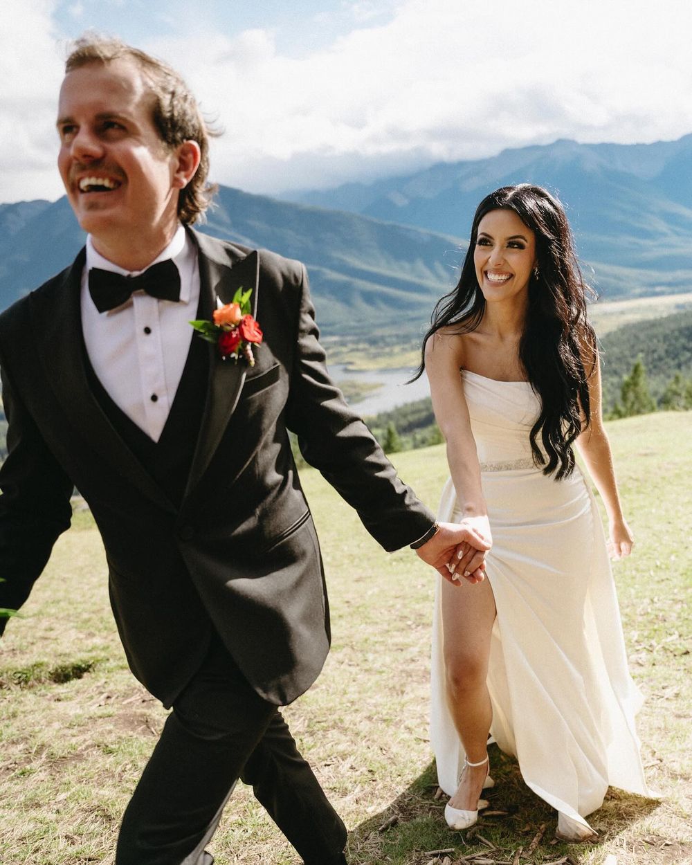 Sarah and Lee walking hand in hand on a Mount Norquay meadow, Banff wedding photographer