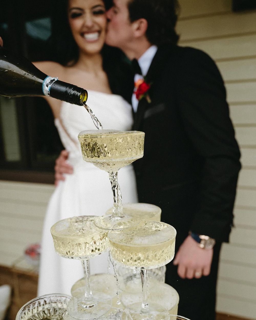 Champagne tower with Sarah and Lee kissing behind, Mount Norquay wedding in Banff