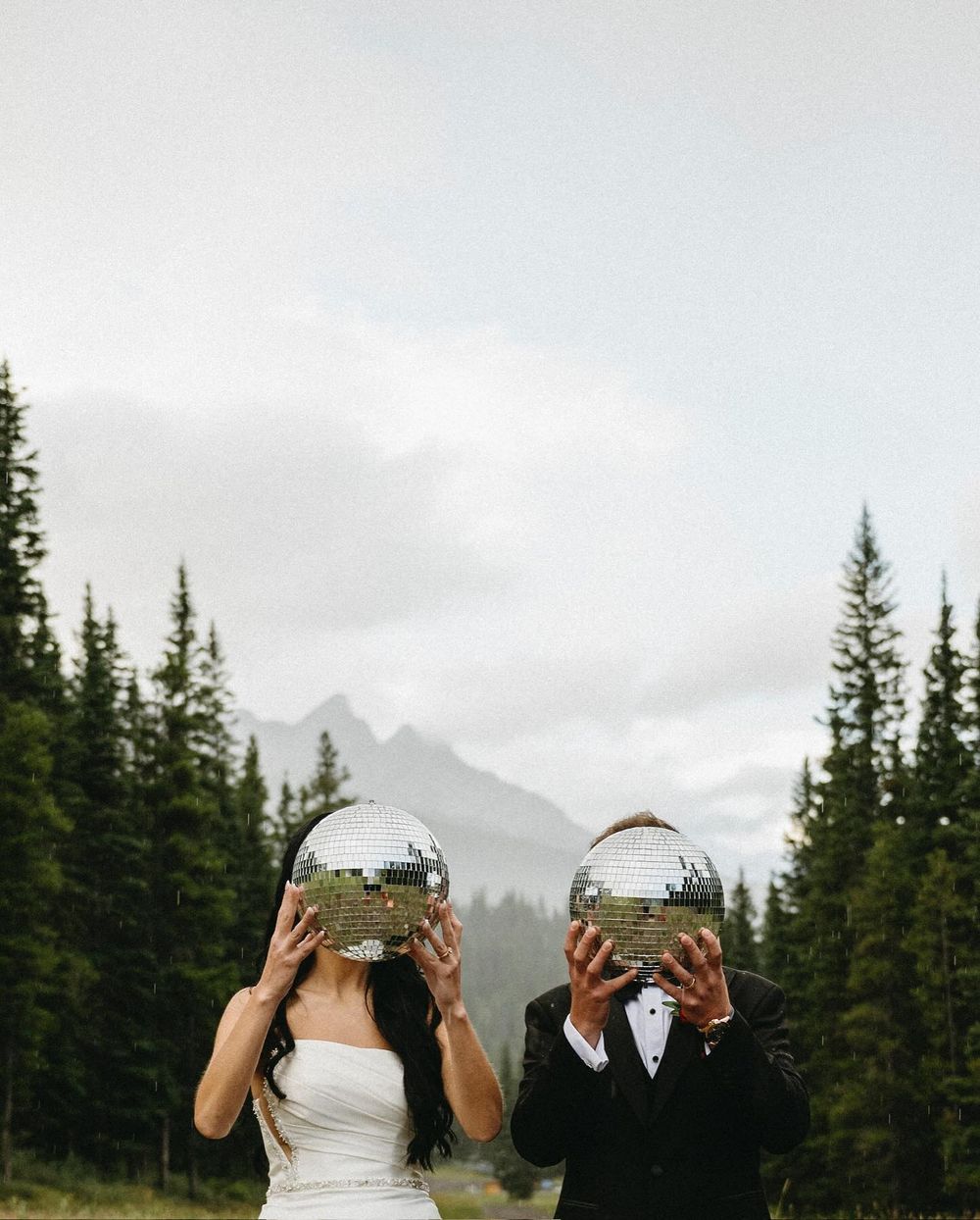 Couple holding disco balls in the pines at Mount Norquay, Banff wedding