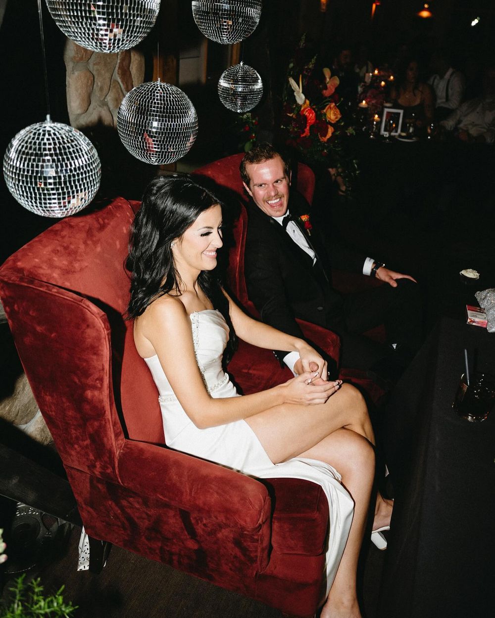 Sarah in a red velvet chair with Lee under disco balls, Mount Norquay lodge