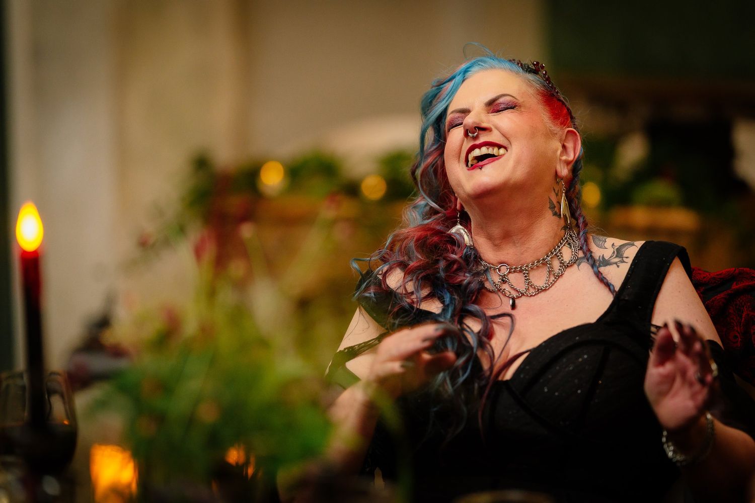 Bride laughing during the wedding speeches beside red candles and flowers