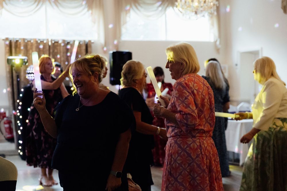 Wedding reception guests socializing and dancing in an elegantly decorated venue with warm lighting.