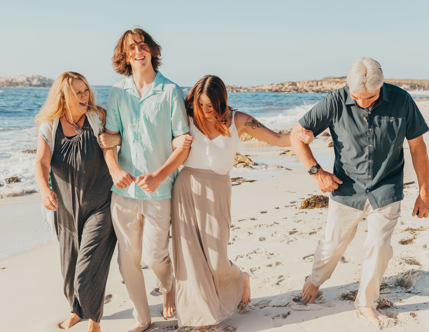 A family laughing and walking on the beach at Pebble Beach
