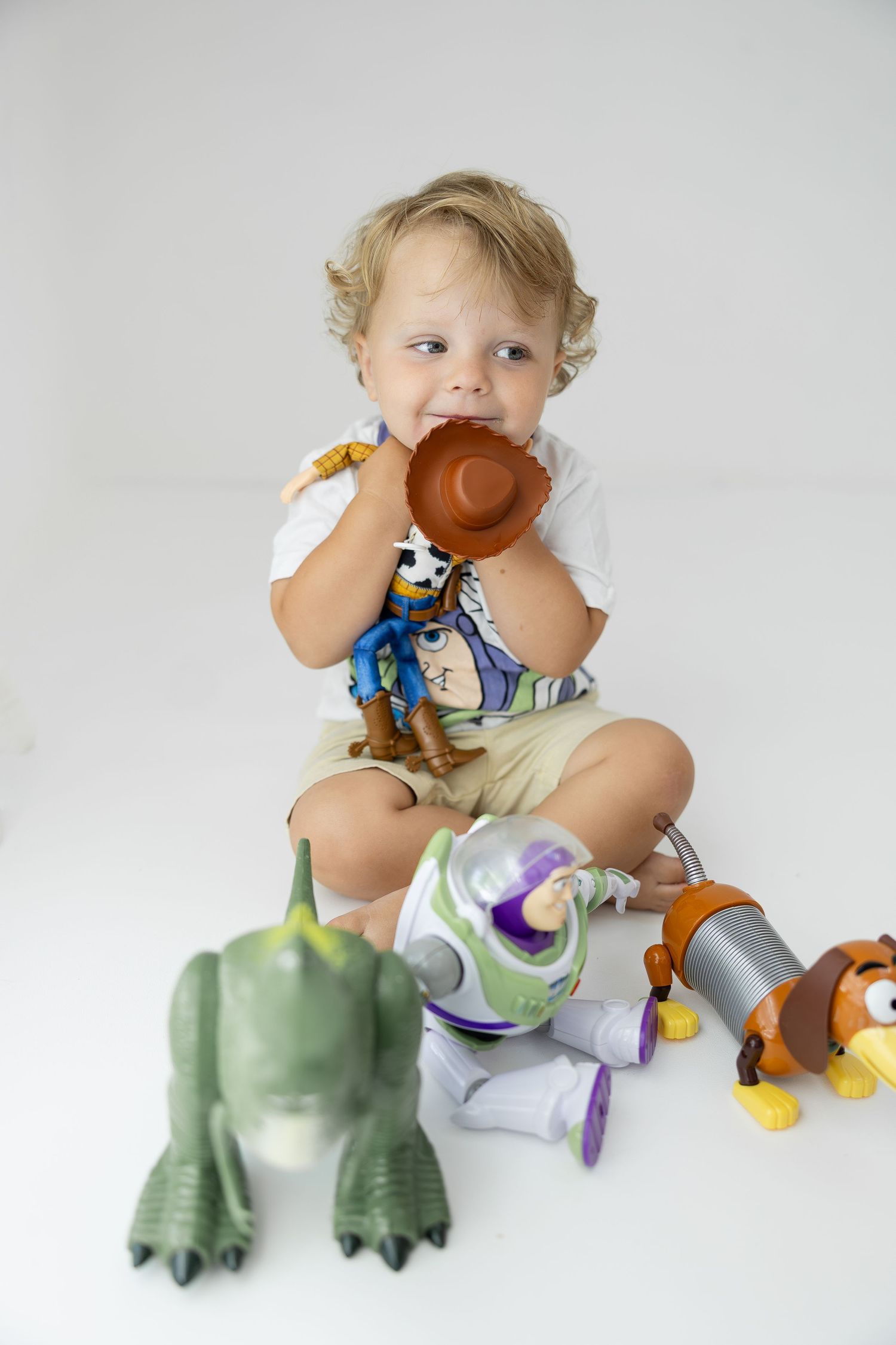Toddler boy plays with Toy Story character figures including Woody, Buzz, Rex, and Slinky Dog.