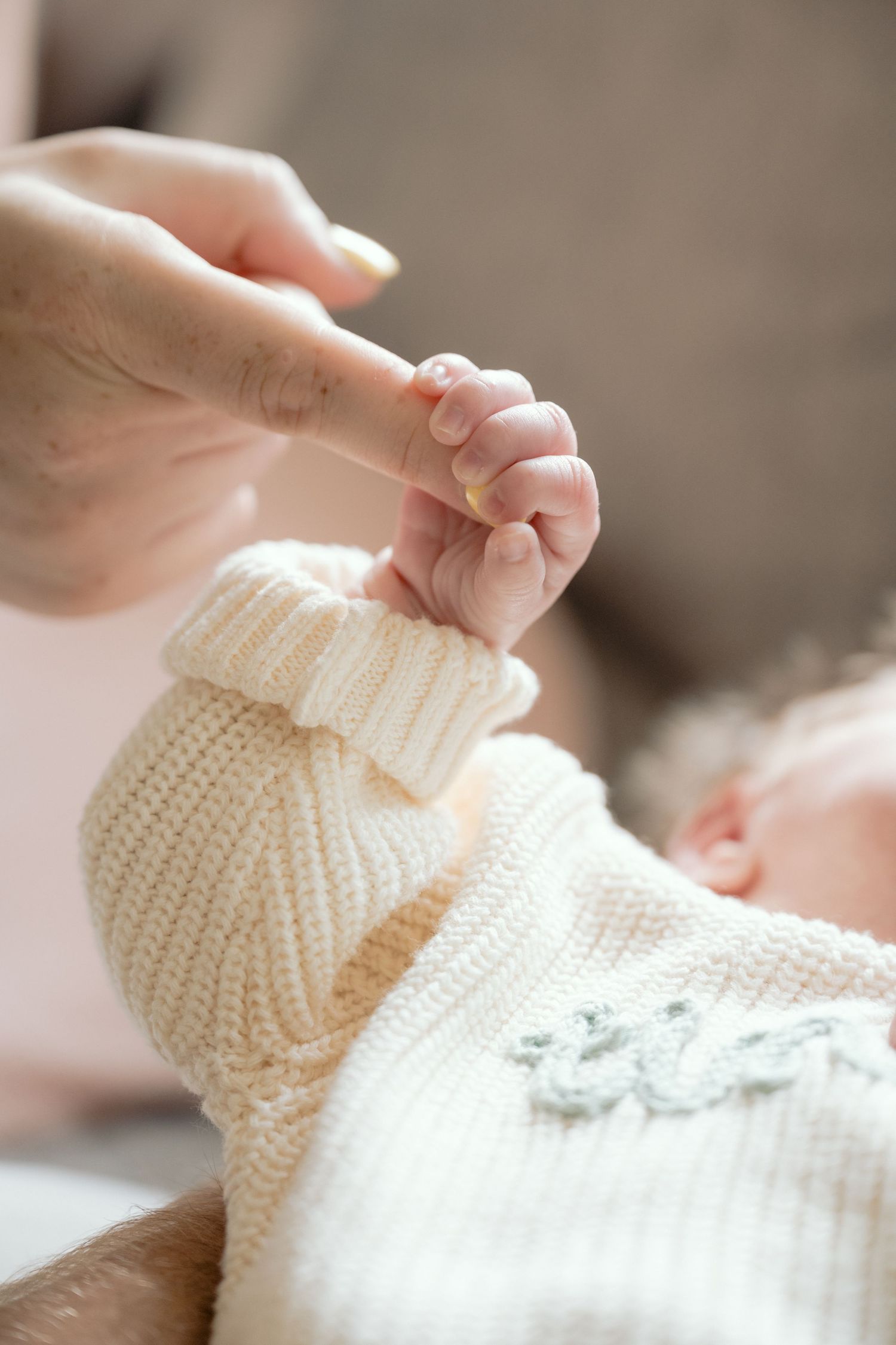 newborn baby curls fingers around moms finger during in home lifestyle newborn session in Minnetonka, MN.